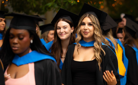 UCD alumni celebrating their graduation, featuring a group of students in academic robes.